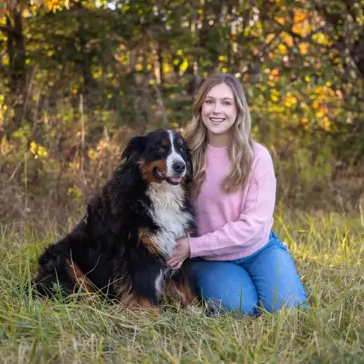 Bernese Mountain Dog sitting outdoors beside its owner